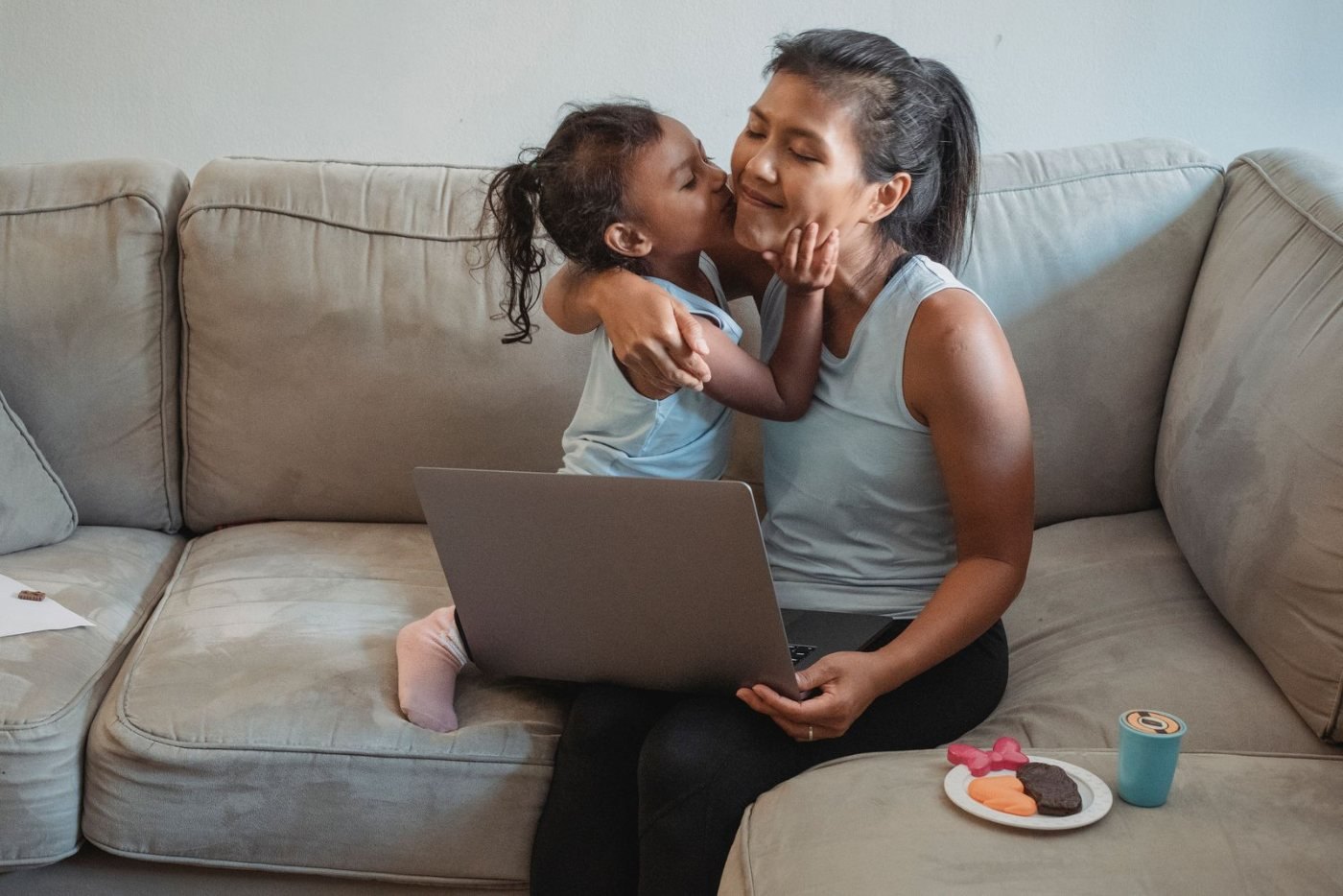 Mother taking an online parenting class on her laptop while her daughter hugs her